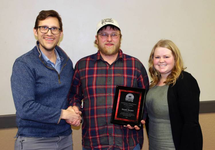 Nathan Kroh from the North Dakota Department of Agriculture, presents Brant and Danesha Naze with the 2024 Commissioner's Award of Dairy Excellence